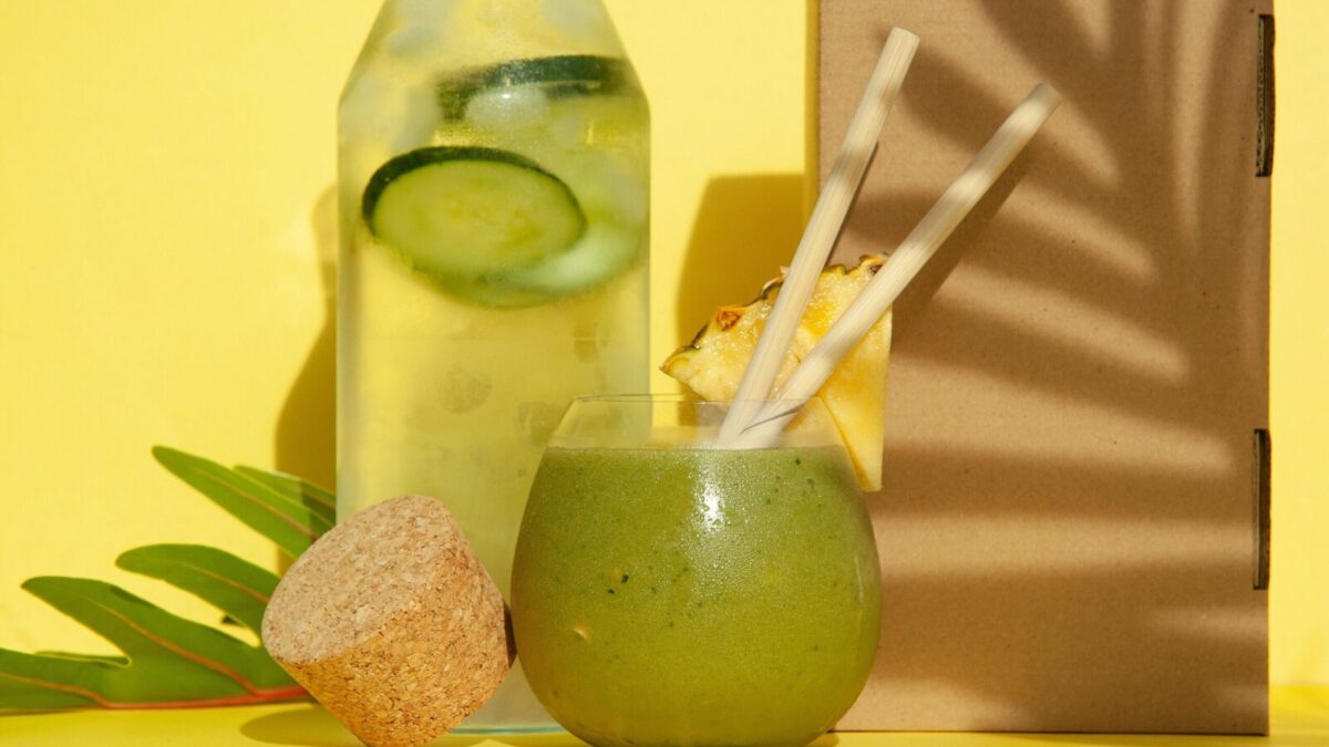 Delicious green smoothie with pineapple and cucumber water against a yellow backdrop. Perfect summer refreshment.