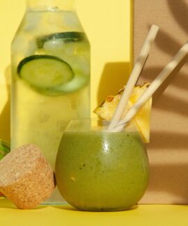 Delicious green smoothie with pineapple and cucumber water against a yellow backdrop. Perfect summer refreshment.