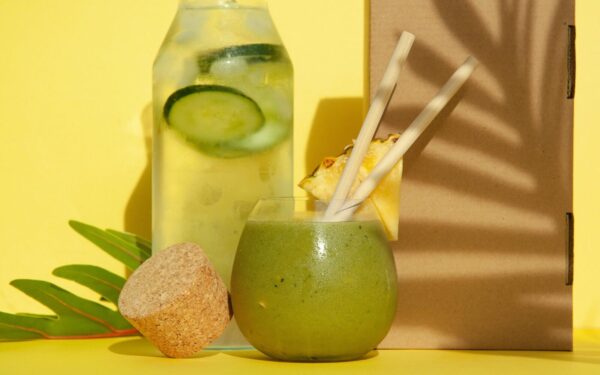 Delicious green smoothie with pineapple and cucumber water against a yellow backdrop. Perfect summer refreshment.