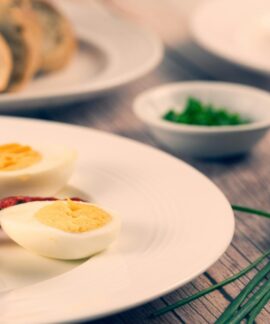 Delicious homemade sliced boiled eggs served with herbs and vegetables on a rustic wooden table.