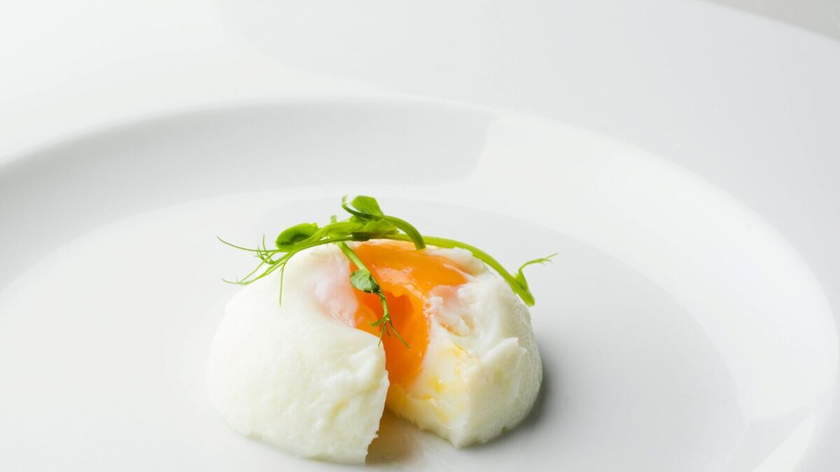 Elegant poached egg with microgreens on a plate, showcasing culinary artistry.