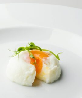 Elegant poached egg with microgreens on a plate, showcasing culinary artistry.