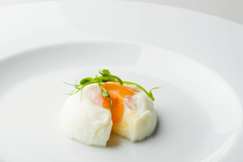 Elegant poached egg with microgreens on a plate, showcasing culinary artistry.
