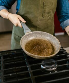Chef holding frying pan with olive oil in kitchen, ready to cook a delicious meal.