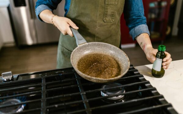 Chef holding frying pan with olive oil in kitchen, ready to cook a delicious meal.