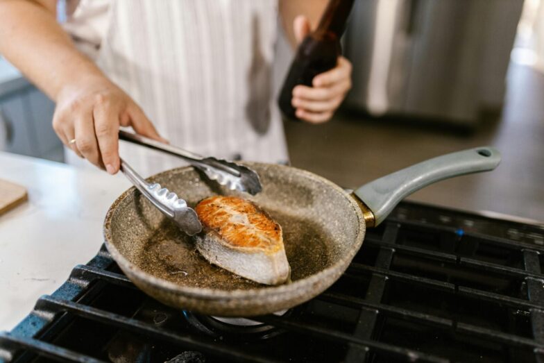 A close-up shot of a salmon steak being grilled in a non-stick pan in a kitchen setting. Perfect for cooking enthusiasts.
