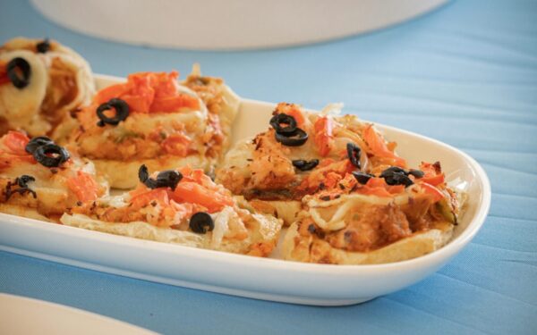 Delicious mini pizzas topped with black olives and tomatoes on a white dish.