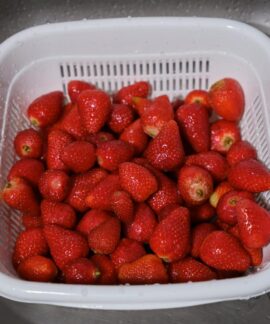 A close-up of fresh strawberries in a white plastic colander. Perfect for healthy eating concepts.
