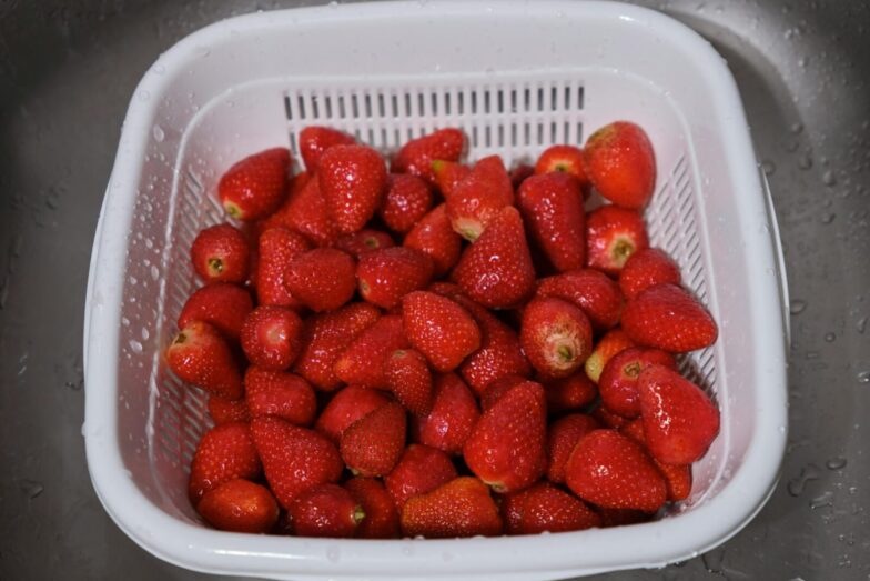 A close-up of fresh strawberries in a white plastic colander. Perfect for healthy eating concepts.