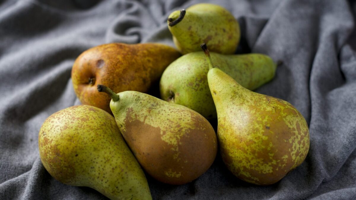 A close-up view of ripe and fresh pears displayed on soft gray fabric, showcasing their natural texture and color.