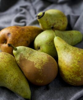 A close-up view of ripe and fresh pears displayed on soft gray fabric, showcasing their natural texture and color.