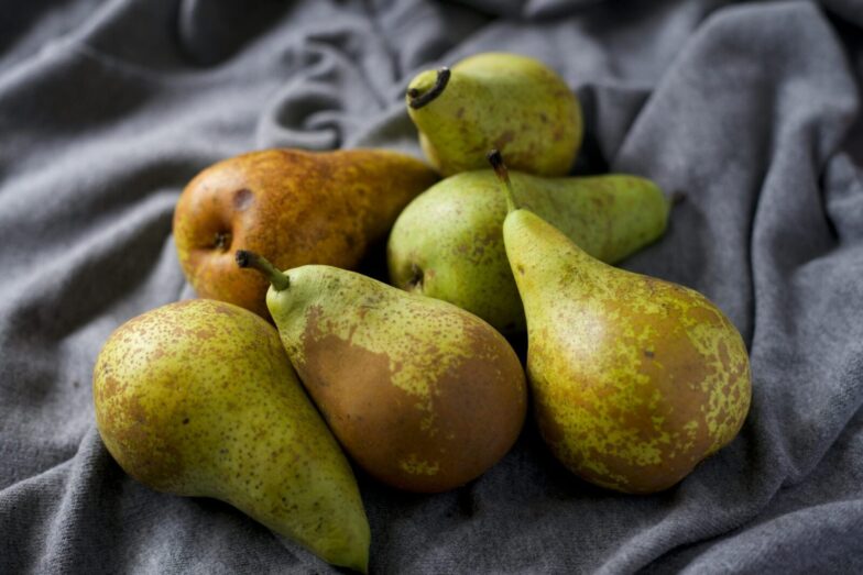 A close-up view of ripe and fresh pears displayed on soft gray fabric, showcasing their natural texture and color.