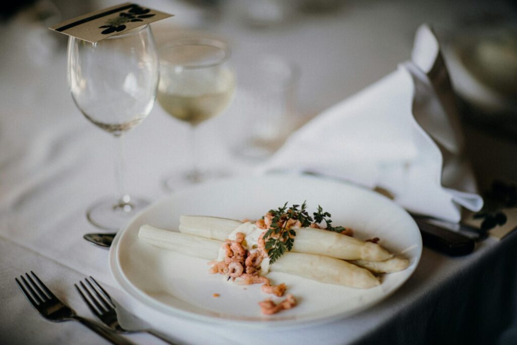 A gourmet asparagus plate with garnish on a table set for fine dining.