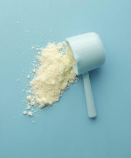 White powder spilled from a scoop on bright blue background. Clean and minimalistic food photo.