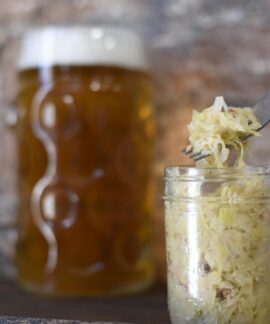 A rustic setting featuring a frothy beer mug and sauerkraut in a jar, perfect for pub themes.