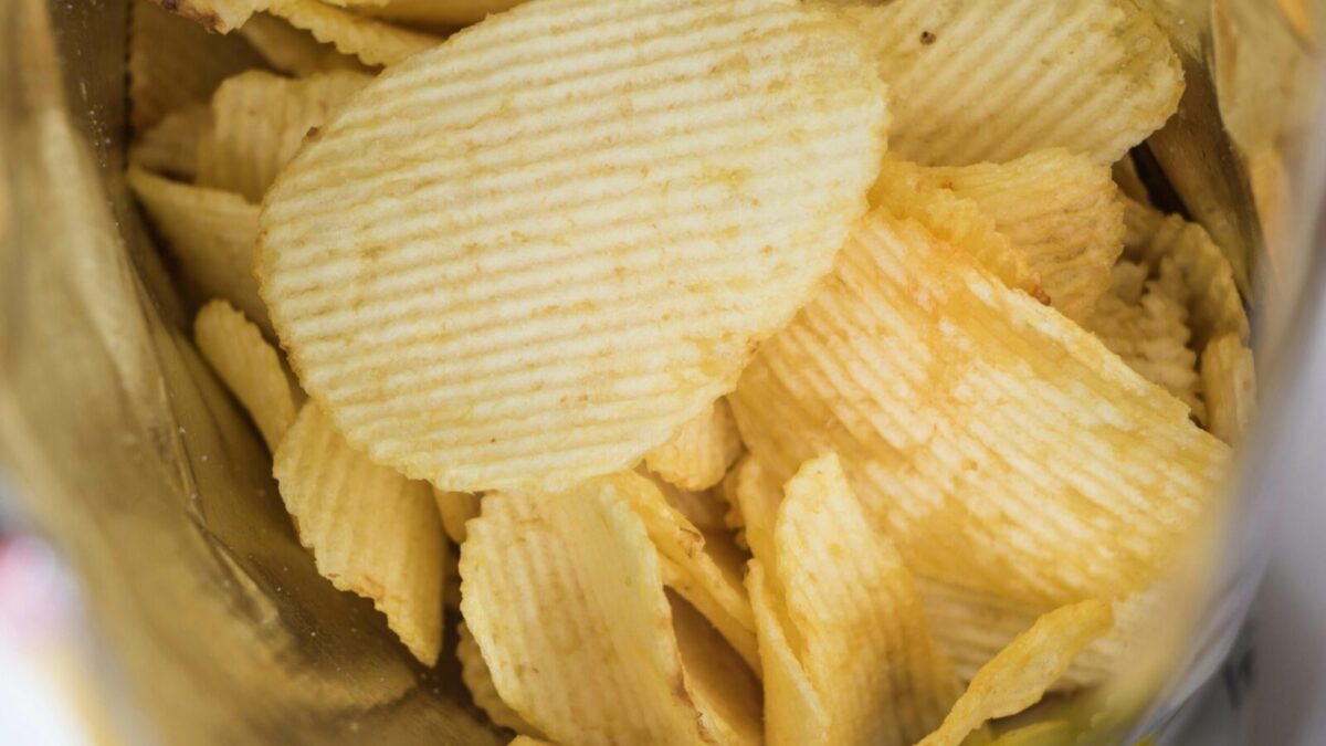 A detailed look at crispy ridged potato chips in an open snack bag, highlighting flavor and texture.