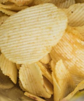 A detailed look at crispy ridged potato chips in an open snack bag, highlighting flavor and texture.