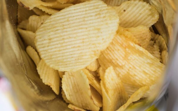 A detailed look at crispy ridged potato chips in an open snack bag, highlighting flavor and texture.