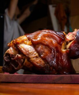 Close-up of a crispy roasted pork knuckle on a wooden cutting board, perfect for stock imagery.