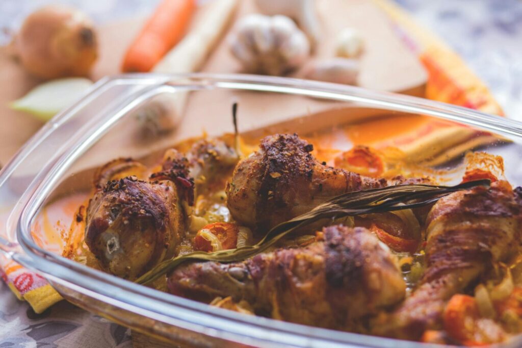 Delicious roasted chicken drumsticks with vegetables in a glass dish, perfect for a family meal.