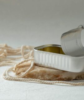 An open metal can rests artfully on a rock surrounded by string, creating a minimalist composition.