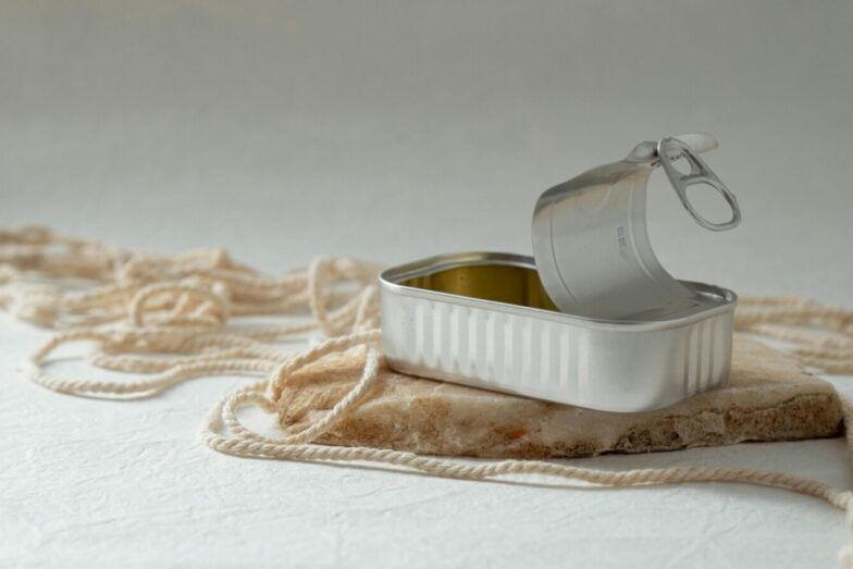 An open metal can rests artfully on a rock surrounded by string, creating a minimalist composition.