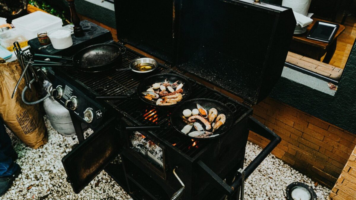 An outdoor barbecue grill with prawns and seafood cooking in cast iron pans. Perfect for a delicious meal.