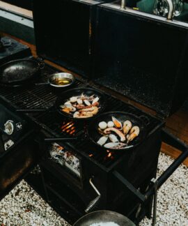 An outdoor barbecue grill with prawns and seafood cooking in cast iron pans. Perfect for a delicious meal.
