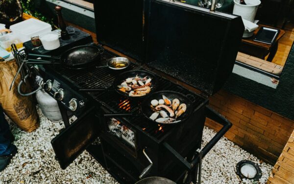 An outdoor barbecue grill with prawns and seafood cooking in cast iron pans. Perfect for a delicious meal.