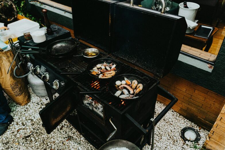 An outdoor barbecue grill with prawns and seafood cooking in cast iron pans. Perfect for a delicious meal.