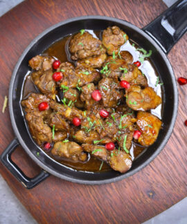 Delicious meat stew served with pomegranate seeds in a rustic pan.