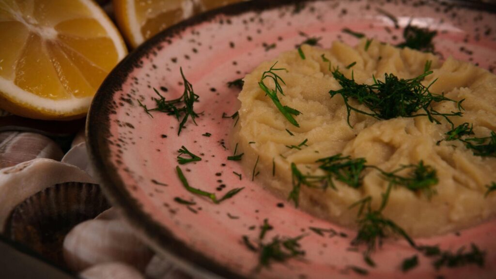 Close-up of a Mediterranean mezze dish garnished with fresh dill and lemon slices, captured in warm tones.