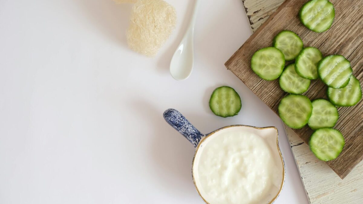 Top view of fresh cucumber slices and creamy yogurt on a rustic wooden board, ideal for healthy eating concepts.