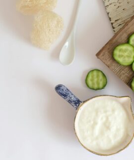 Top view of fresh cucumber slices and creamy yogurt on a rustic wooden board, ideal for healthy eating concepts.