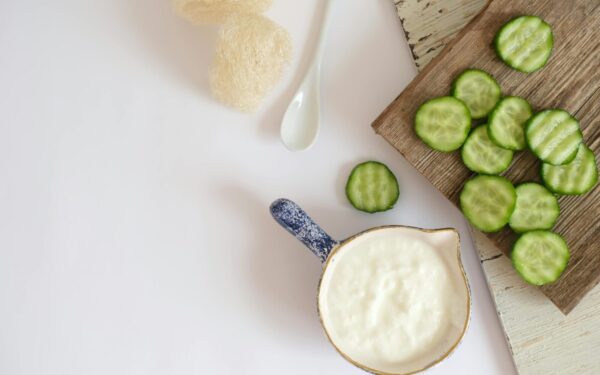Top view of fresh cucumber slices and creamy yogurt on a rustic wooden board, ideal for healthy eating concepts.
