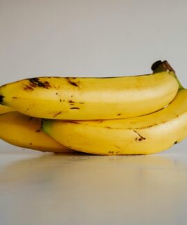A bunch of fresh yellow bananas stacked elegantly on a smooth white surface, ready to eat.