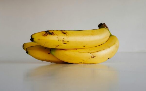 A bunch of fresh yellow bananas stacked elegantly on a smooth white surface, ready to eat.