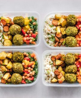 Colorful meal prep containers with falafel, chickpeas, rice, and vegetables for a healthy lifestyle.