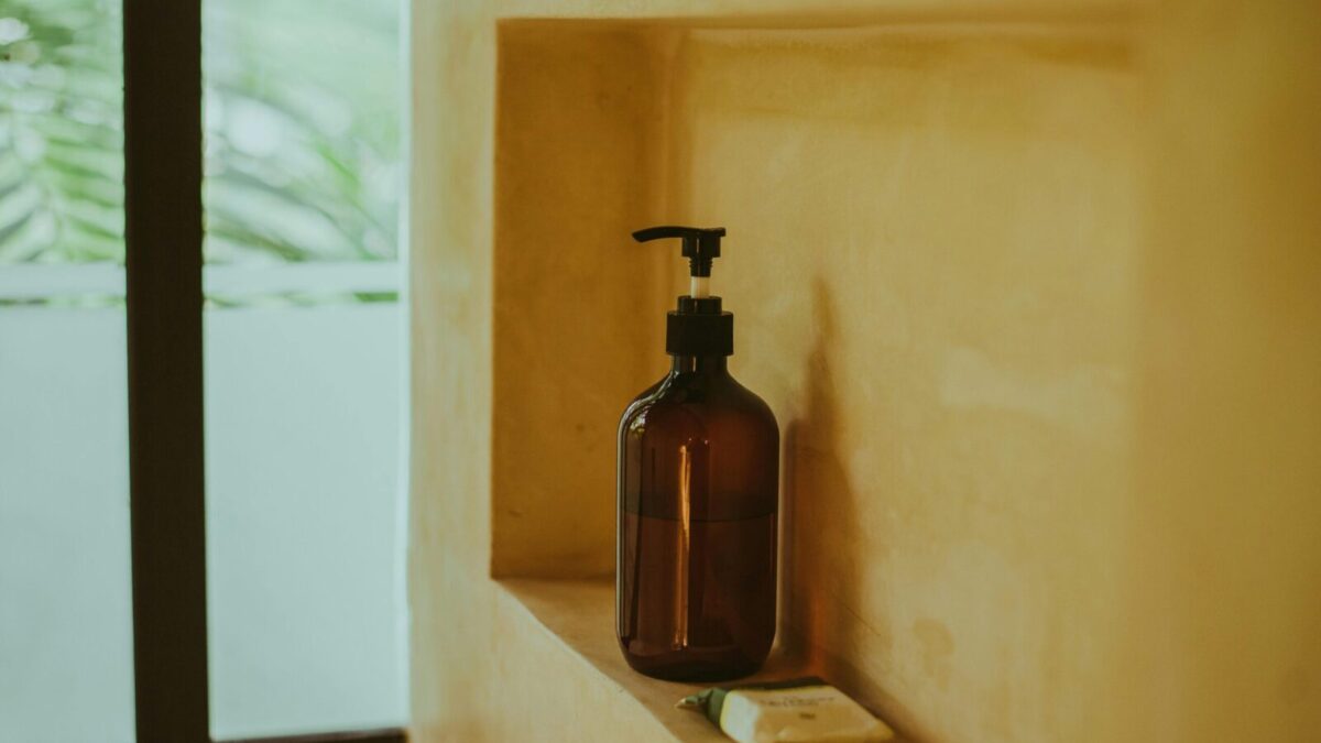 A minimalist bathroom shelf showcasing an amber soap dispenser and bar soap, exuding elegance.