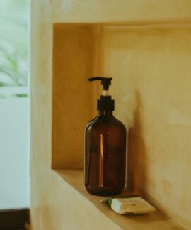 A minimalist bathroom shelf showcasing an amber soap dispenser and bar soap, exuding elegance.