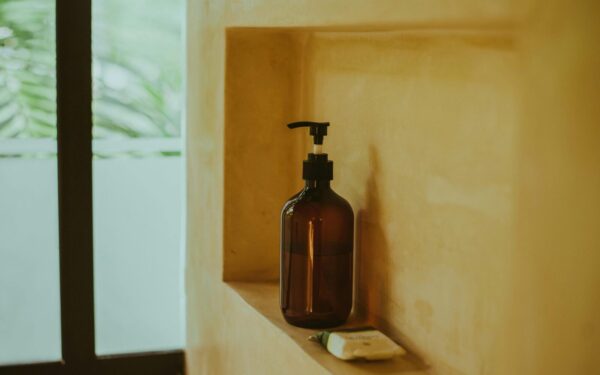 A minimalist bathroom shelf showcasing an amber soap dispenser and bar soap, exuding elegance.