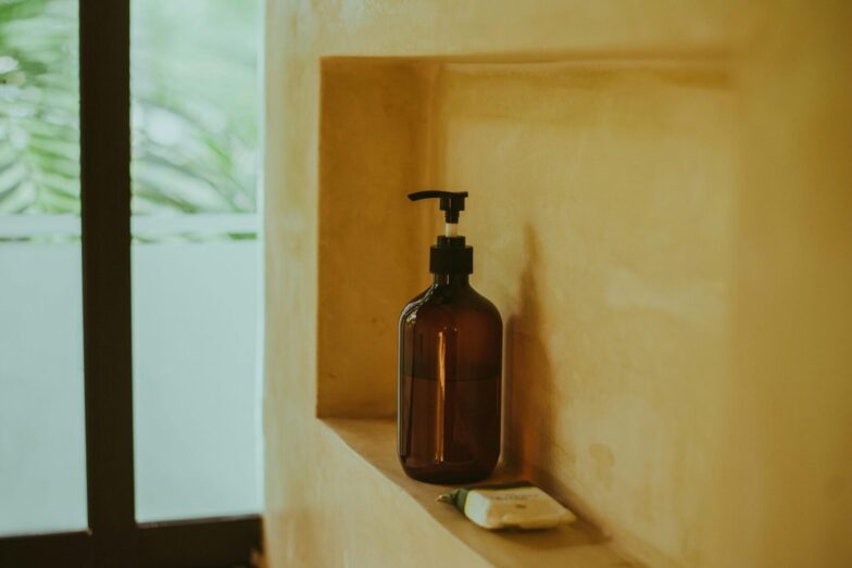 A minimalist bathroom shelf showcasing an amber soap dispenser and bar soap, exuding elegance.