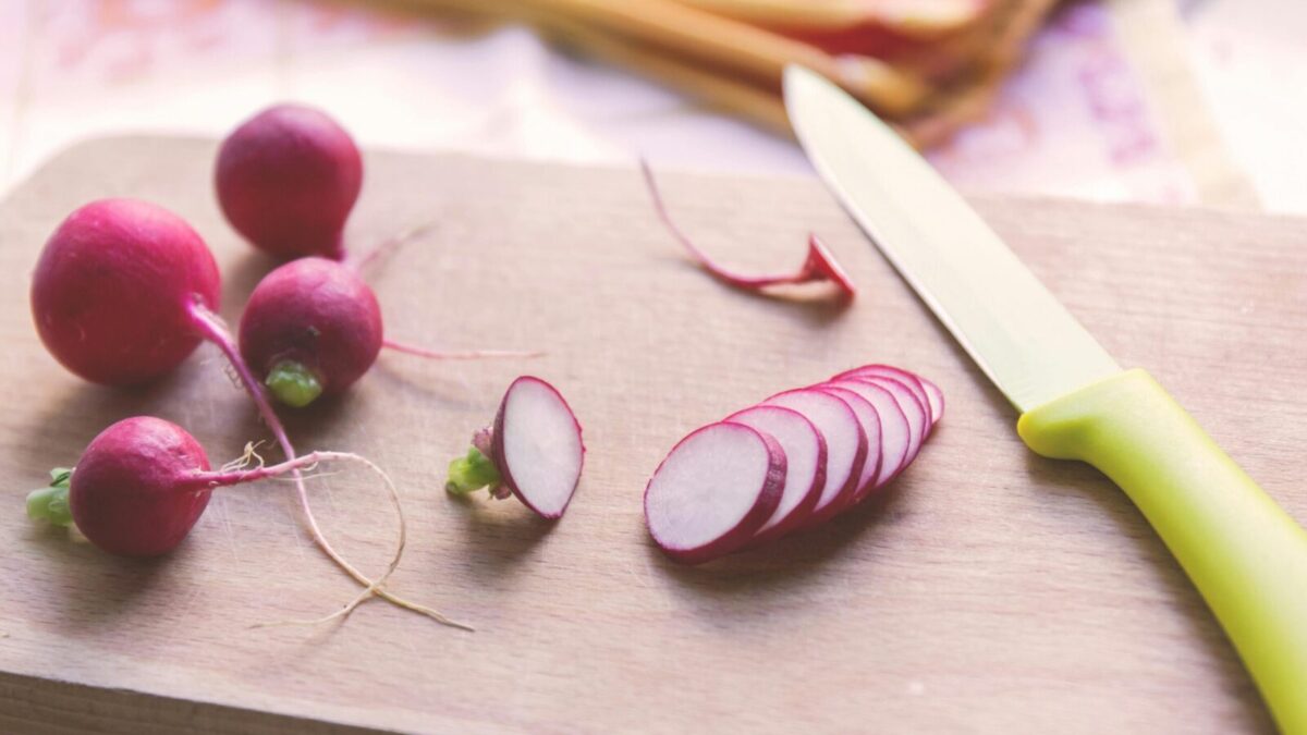 Freshly sliced radishes on a cutting board with a knife, perfect for healthy recipes.