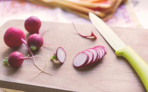 Freshly sliced radishes on a cutting board with a knife, perfect for healthy recipes.