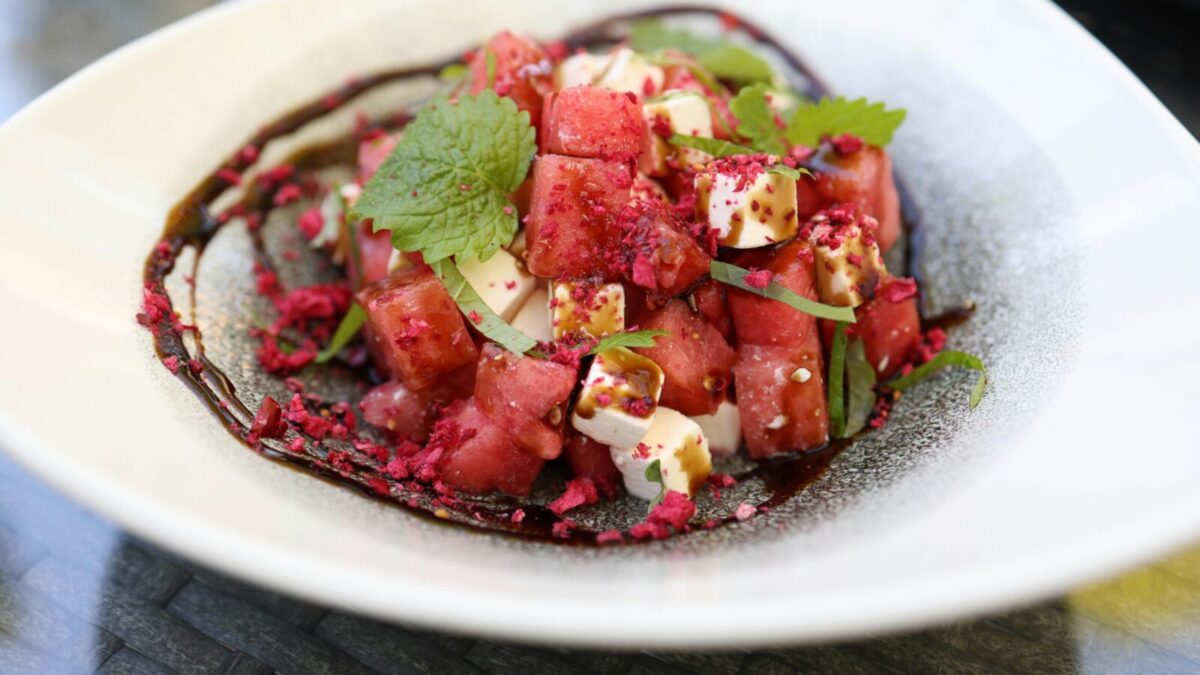 Close-up image of a vibrant watermelon and feta salad garnished with mint leaves.