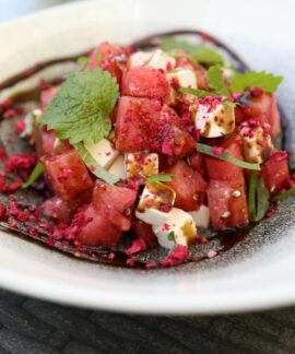 Close-up image of a vibrant watermelon and feta salad garnished with mint leaves.