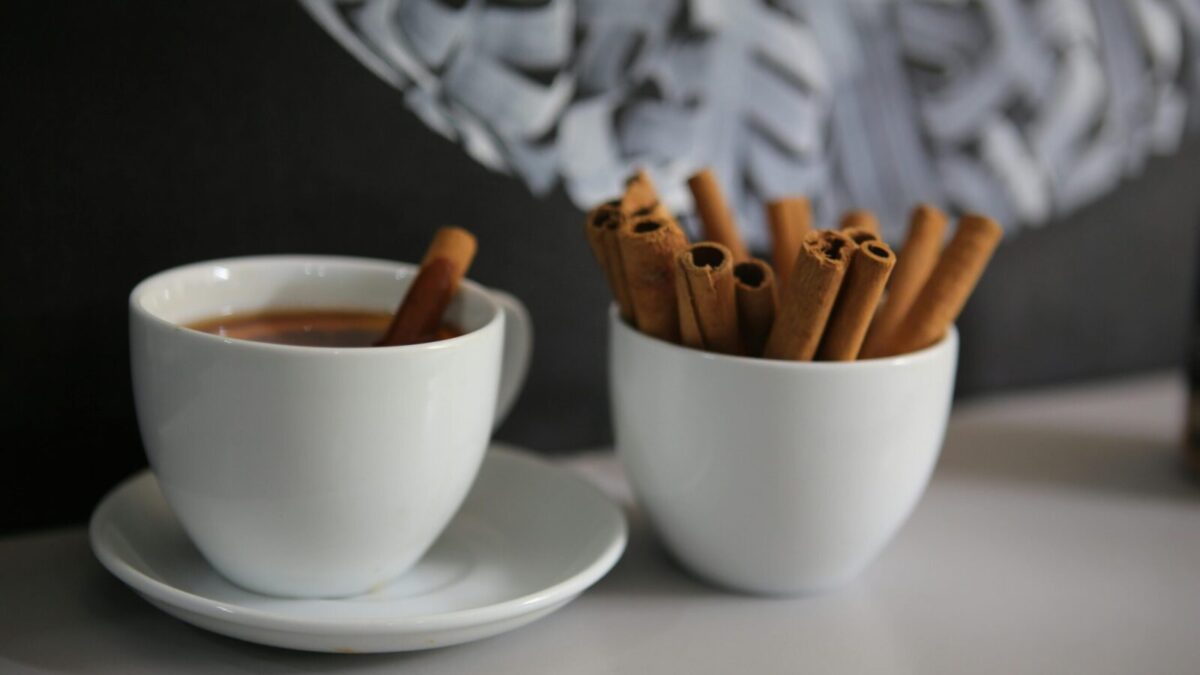 A cozy cup of coffee with cinnamon sticks on a table, creating a warm atmosphere.