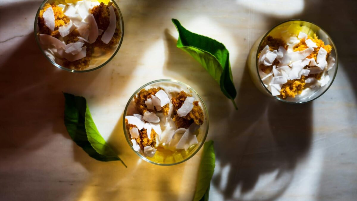 Top view of dessert with coconut shards, leaves, and shadows creating a warm ambiance.