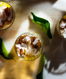 Top view of dessert with coconut shards, leaves, and shadows creating a warm ambiance.