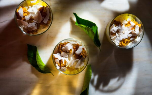 Top view of dessert with coconut shards, leaves, and shadows creating a warm ambiance.